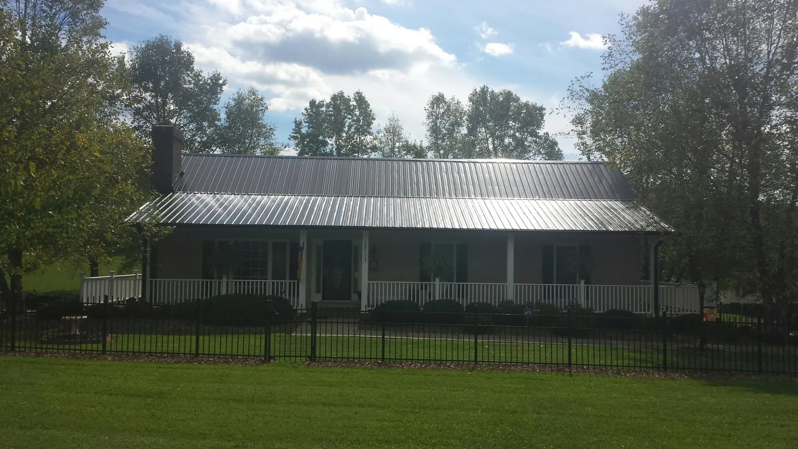 Gray metal roof on a brick ranch with a full width front porch — Gutter Guard Installation work by our crew in Fredericksburg